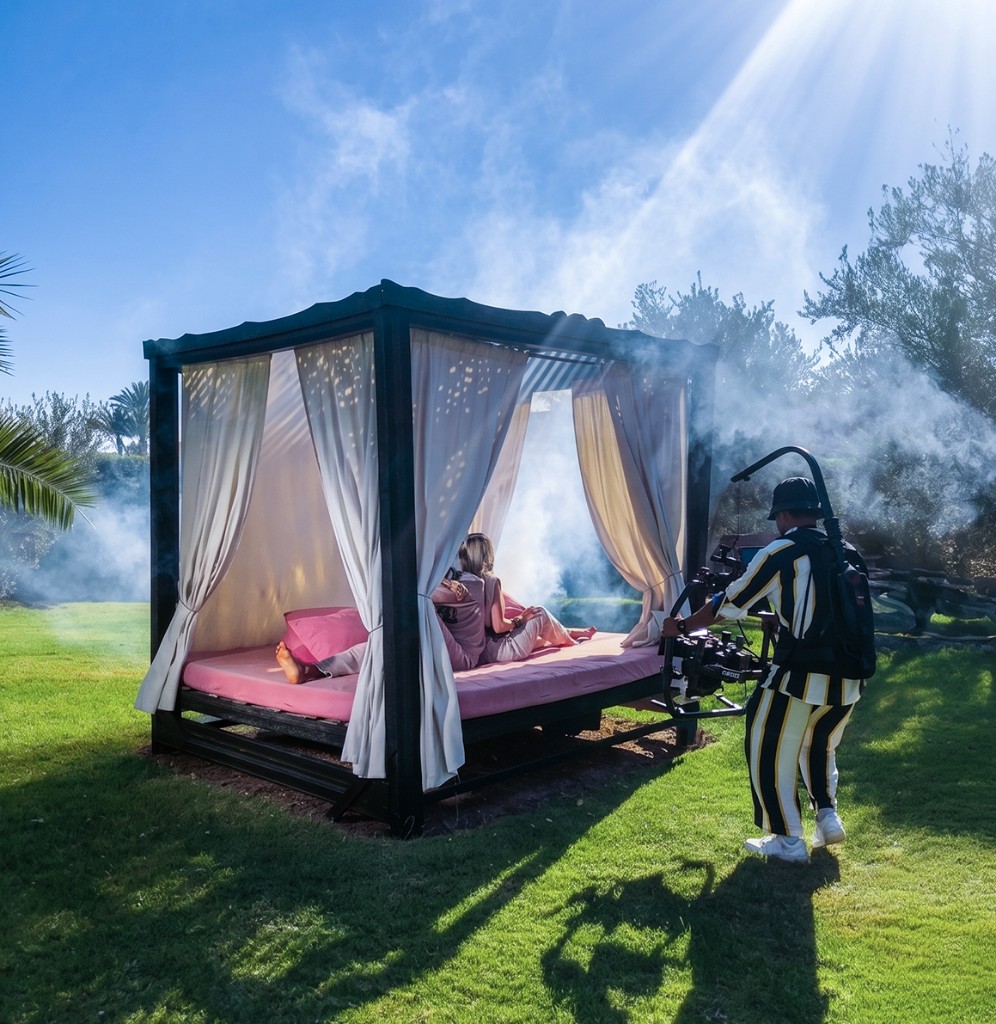 AdKey Prod music video shoot in Morocco — cinematographer behind a gimbal-mounted cinema camera, talent on a daybed surrounded by atmospheric haze