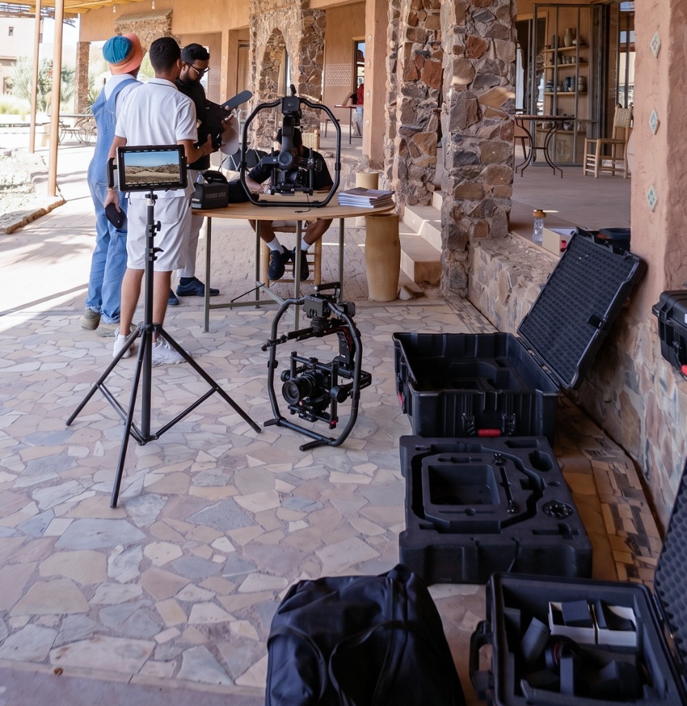 Video producer in Morocco — daytime music video setup outside a stone-built villa with gimbal, monitor, tripods and pelican cases on location